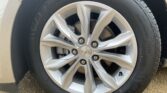 Close-up of a black tire mounted on a silver multi-spoke alloy wheel with a Chevrolet emblem at the center, resting on a gravel surface.