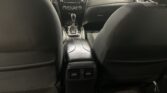 View from the back seat of a dark-car interior: center console with a touchscreen and gear lever, flanked by front seats and rear air vents behind them.