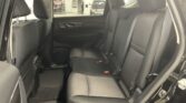 Back seat area of a dark SUV with gray cloth seats and headrests; view through rear door toward a workshop outside the car door.