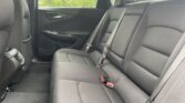 Rear passenger area of a car with black fabric seats, three-seat belt setup, and headrests visible in a sedan/SUV interior.