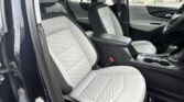 Front seats in a modern car with light gray quilted upholstery and a center console visible from the passenger side window open.