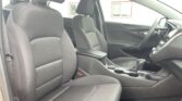 Front interior of a dark fabric car with two seats, center console with cup holders, and a right-side steering wheel visible.