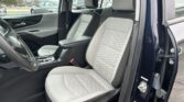 Front and passenger seats of a vehicle with light gray quilted upholstery, view from the open front door showing the interior.