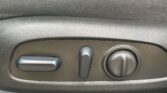 Close-up of a car seat adjustment panel with a horizontal lever, a vertical lever, and a round knob on a textured surface.