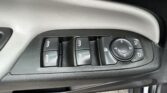 Car door control panel with four window switches and a circular mirror-adjustment joystick on a textured door trim