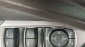 Car dashboard controls: window switches on the left and a circular multi-button dial with arrows on the right, plus a small mute icon beneath the dial