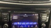 Car infotainment screen showing FM radio at 101.5 FM with preset buttons and surrounding physical controls on a glossy dashboard.