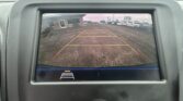 Rear-view camera display showing a parking lot with orange guide lines for reversing.
