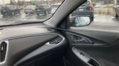View from inside a car showing a parking lot with several SUVs through the windshield and in the side mirror, on a chilly day with patches of snow on the ground.