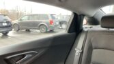 Backseat view from inside a parked car looking out at gray SUVs in a parking lot. (informative)