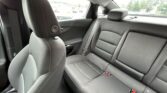 Backseat of a dark gray car with two outer seats, center seat, headrests, and visible seat belts outside the window.