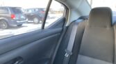 Backseat view inside a car showing a vertical seat belt and headrest, with a snowy parking lot and black SUVs outside the window.