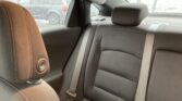 Rear passenger seat area of a car with black fabric upholstery, a brown headrest in the foreground, and visible seat belts.