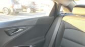 Interior of a car's back seat and door panel, with a seatbelt buckle visible; outside the window is a parking lot with parked SUVs