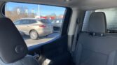 Interior of a car viewed from the back seat, showing the rear passenger area and window to a parking lot with silver SUVs outside.