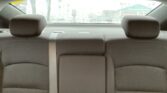 Interior of a car's back seat viewed from the rear, with raindrop-covered rear window and blurred street scene outside