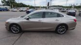 Silver Chevrolet Impala sedan viewed from the side in a car dealership lot, with other vehicles in the background.