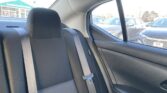 Back seat of a car with gray fabric upholstery and a loose three-point seat belt across the seat.