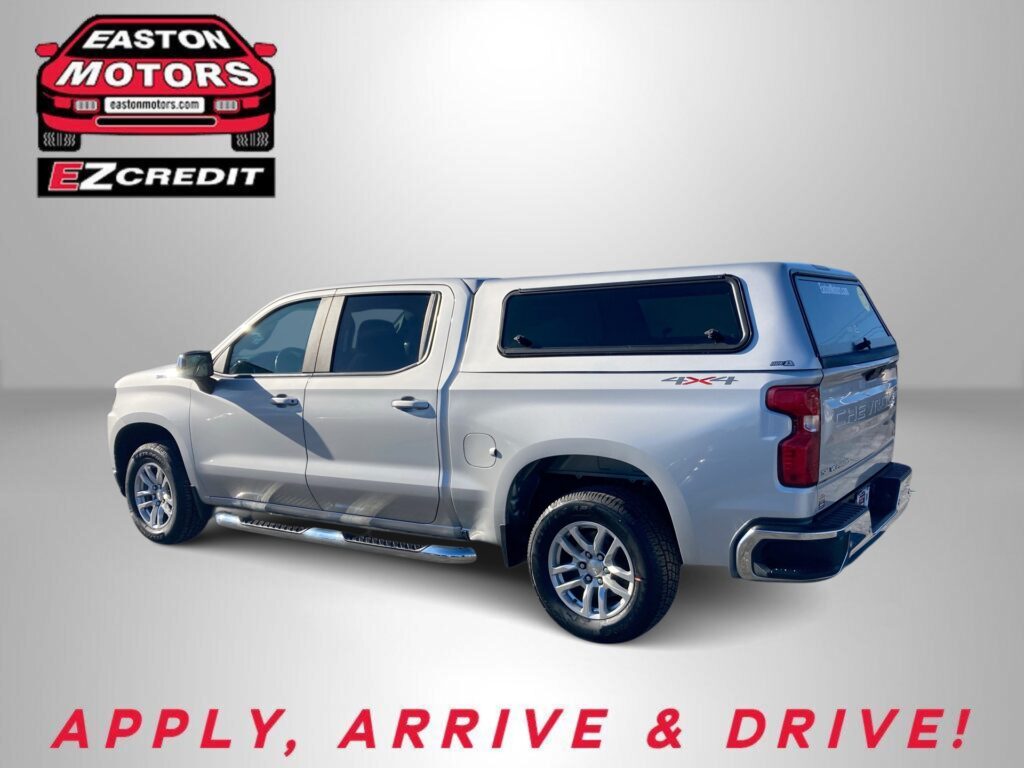 Silver pickup truck with a camper shell on a gray gradient background; Easton Motors and EZ Credit branding in the top-left corner, and 'APPLY, ARRIVE & DRIVE!' text at the bottom.