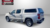 Silver pickup truck with a camper shell on a gray gradient background; Easton Motors and EZ Credit branding in the top-left corner, and 'APPLY, ARRIVE & DRIVE!' text at the bottom.