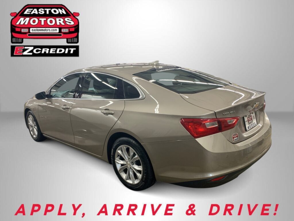 Gold Chevrolet sedan displayed in a showroom with Easton Motors EZCredit logo in the upper left and 'APPLY, ARRIVE & DRIVE!' text beneath
