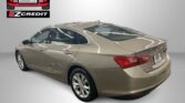 Gold Chevrolet sedan displayed in a showroom with Easton Motors EZCredit logo in the upper left and 'APPLY, ARRIVE & DRIVE!' text beneath