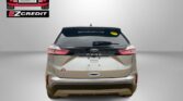 Rear view of a beige Ford Edge SUV with Easton Motors branding in the top-left corner and 'APPLY, ARRIVE & DRIVE!' slogan at the bottom.