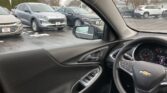 View from the driver's seat of a car in a dealership lot, showing parked cars outside through the windshield.