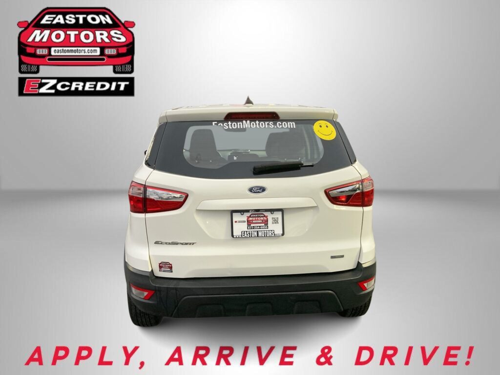 Rear view of a beige Ford SUV with EZCredit branding on the back window and a smiley sticker on the right window; dealership ad background shows 'APPLY, ARRIVE & DRIVE!' text at bottom.