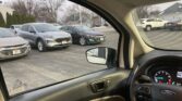Photo from inside a car showing a parking lot with multiple SUVs and sedans, side mirror in view, dashboard on the right side, Ford badge visible on the wheel.