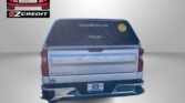 Rear view of a silver Chevrolet Silverado with a yellow smiley decal on the rear window and the 'Easton Motors' logo in the upper left; large red 'APPLY, ARRIVE & DRIVE!' text at bottom.