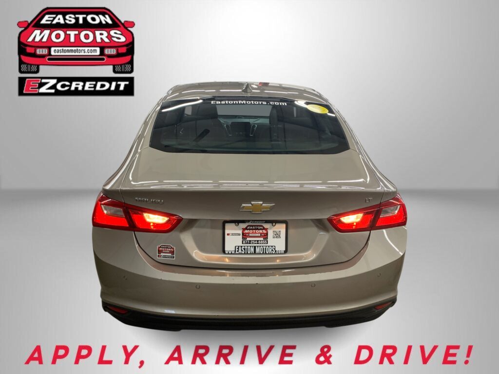 Rear view of a beige Chevrolet sedan in a showroom, with an Easton Motors logo on the left and the slogan 'APPLY, ARRIVE & DRIVE!' below.