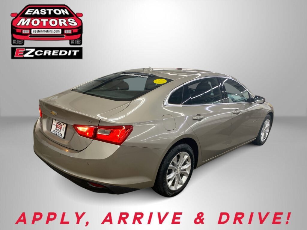 Beige sedan in a showroom with Easton Motors logo on the wall and the slogan 'Apply, Arrive & Drive!' at the bottom