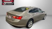 Beige sedan in a showroom with Easton Motors logo on the wall and the slogan 'Apply, Arrive & Drive!' at the bottom
