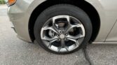 Close-up of the front left wheel on a gray Chevrolet car, showing the alloy rim and tire with the car body in the background.
