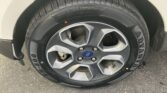 Close-up of a Ford wheel with a black tire and silver multi-spoke rim; red valve cap visible near the valve stem.