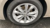 Close-up of a car tire and silver alloy wheel with a Chevrolet logo, wet with rain, showing the rusty brake rotor behind the spokes.