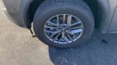 Close-up of a car wheel and tire on a paved surface, showing a Nissan center cap and alloy rim.