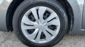 Close-up of a car wheel: silver alloy rim with Nissan center cap and a black tire, on asphalt pavement.
