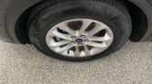 Close-up of a car tire and silver alloy wheel with Ford emblem, showing 'Touring Sport' on the sidewall.