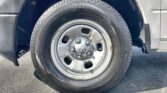 Close-up of a vehicle's front wheel with tire and hubcap, adjacent fender visible in dark and light panels.