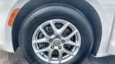 Close-up of a car's front wheel: silver alloy rim, black tire, and an orange side-marker on the fender edge showing part of the body.