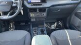 Front cabin of a Ford vehicle: steering wheel with logo, large center touchscreen, climate controls, and gear selector