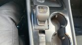 Center console in a car showing the gear selector (P, R, N, D/M), cup holders, and an electronic parking brake button area.