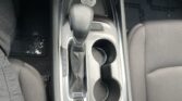 Center console of a car with an automatic gear shifter, two cup holders, and an electronic parking brake button nearby.