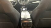 Rear seating area of a dark car interior, view from the back seat toward the front dashboard and center console with vents and touchscreen.