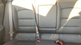 Rear car seat with three sections and visible seat belts and headrests.