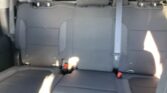 Interior of a car's backseat with gray upholstery, three headrests and visible seat belts, viewed from the rear cargo area.