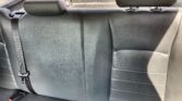 Back seat of a car with black leather upholstery, three seat belts, and headrests visible in the rear row.