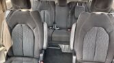 Interior of a dark fabric SUV with two front captain chairs and a rear bench, all with white stitching and visible red seatbelt buckles